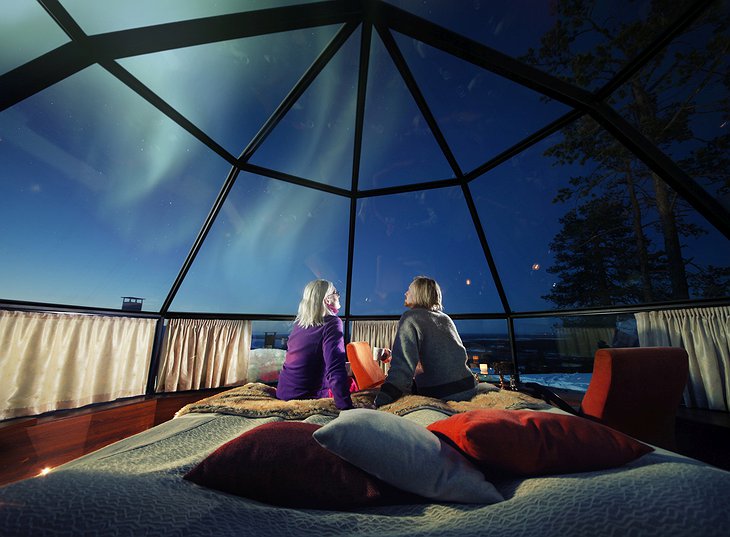 Old couple looking at the Northern Lights from the bed of their igloo at Levin Iglut