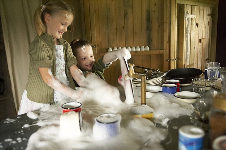 Kids washing the dishes and having fun with the foam