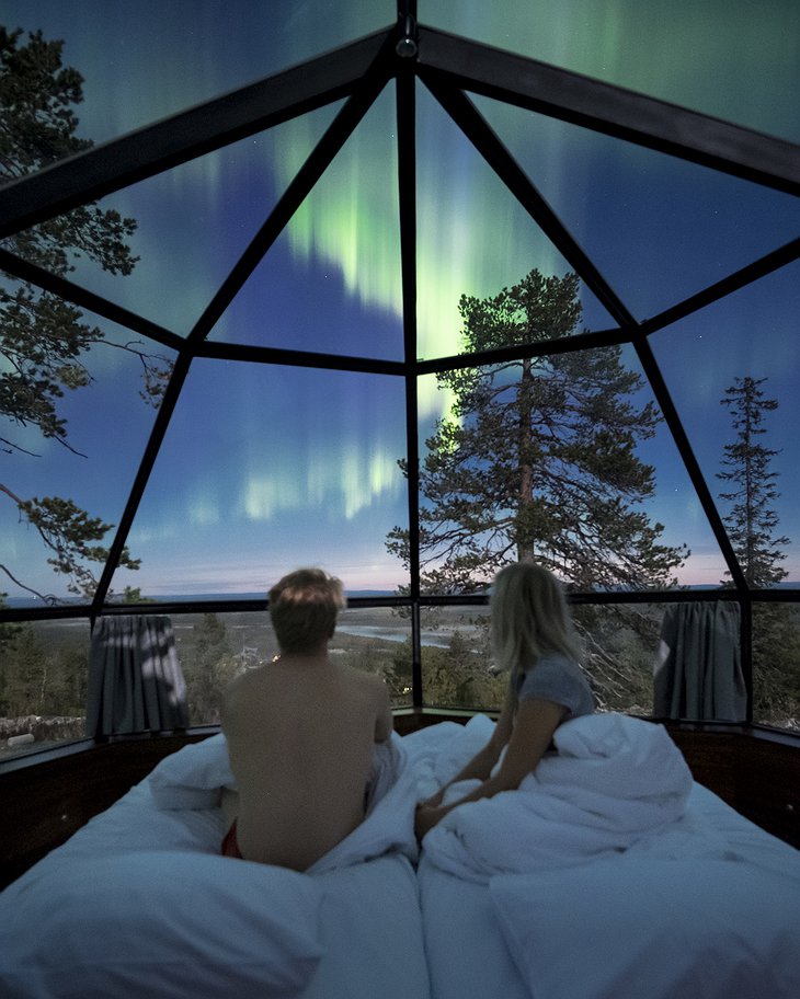Couple in the bed in the igloo staring at the Northern Lights