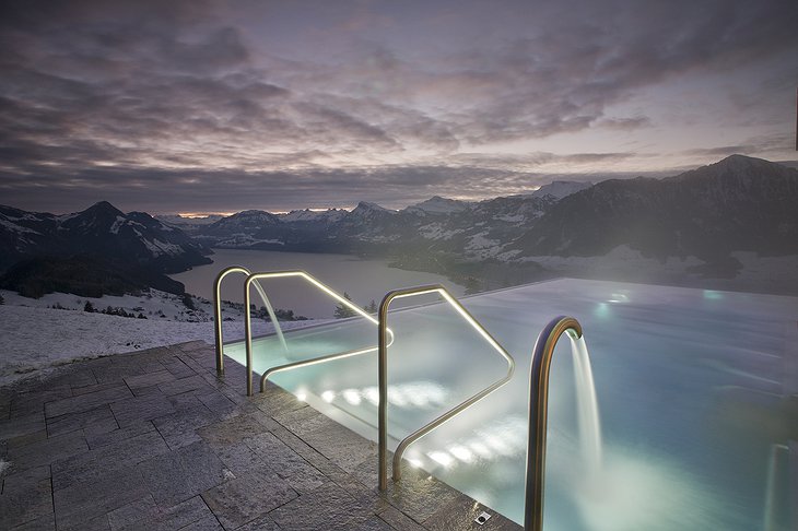 Infinity pool with snowy Alps views at night