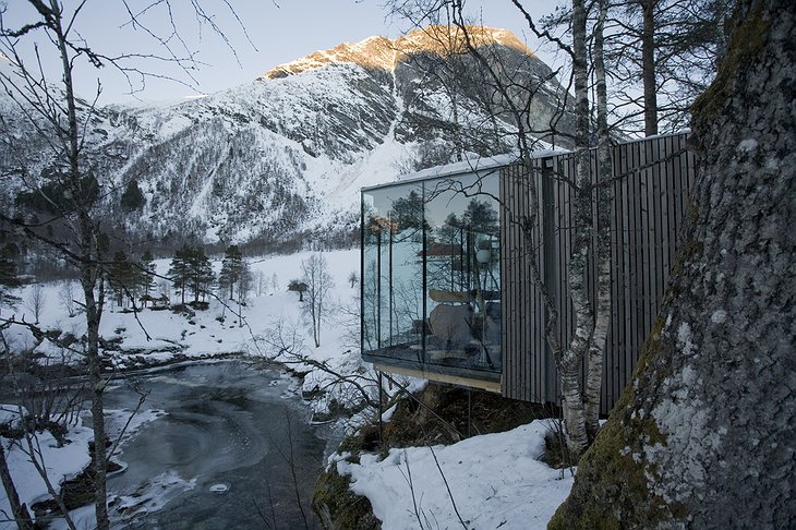 Snowy Norwegian landscape with the glass cabins of Juvet Landscape Hotel