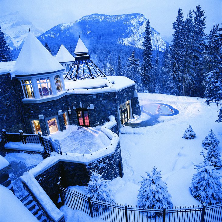 Fairmont Banff Springs Hotel during winter covered in snow and a steaming hot jacuzzi outside
