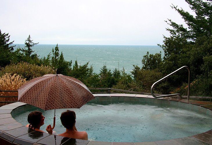 Couple under umbrella in the jacuzzi while it is raining