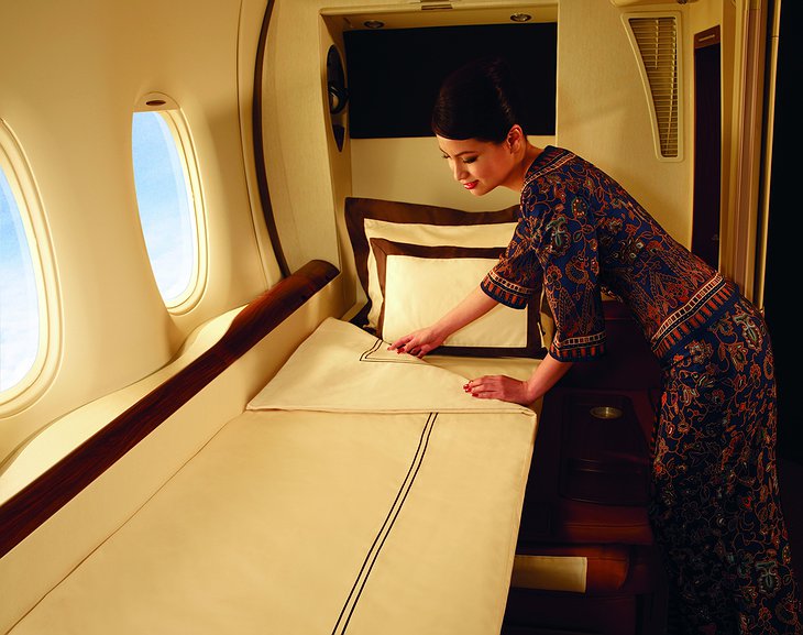 Singapore Airlines stewardess makes the bed in the luxury suite cabin