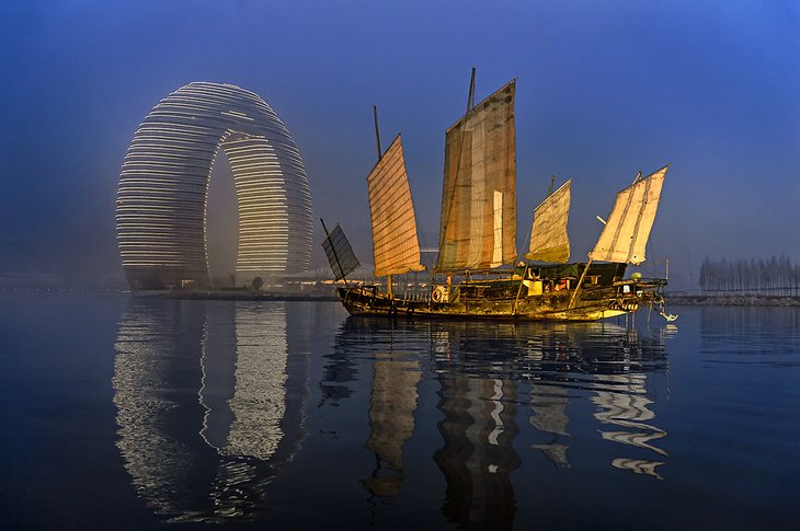 Sheraton Huzhou Hot Spring Resort at night and an old sailing boat on the sea