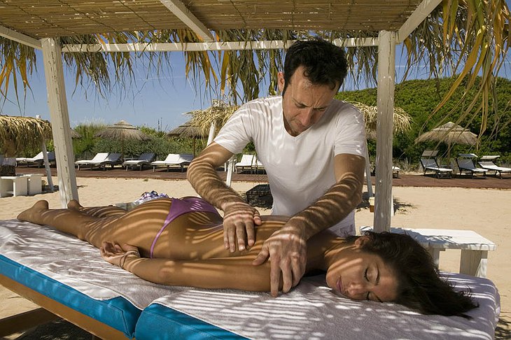 Beautiful topless girl getting a massage on the beach