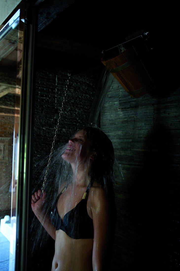 Girl using cold bucket shower after sauna