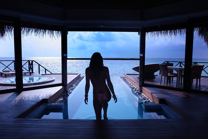 Girl entering the water of the private infinity pool on Maldives